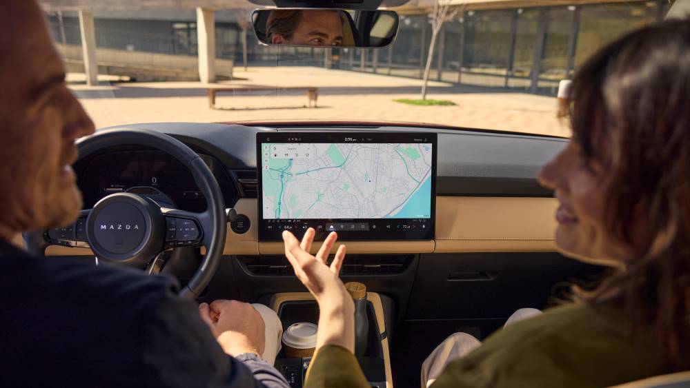Couple in front seats of a 2026 Mazda CX-5 with view of infotainment system