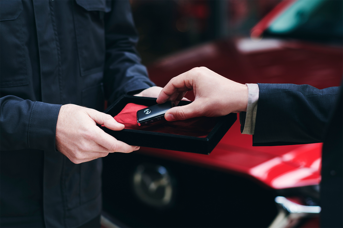 Mazda car passing between hands in car showroom
